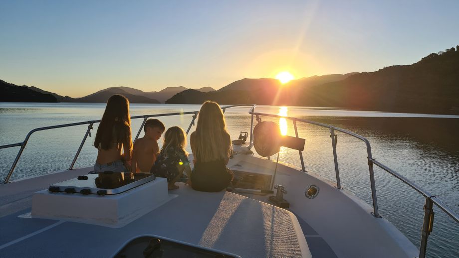 family enjoying a sunset on the front of their boat